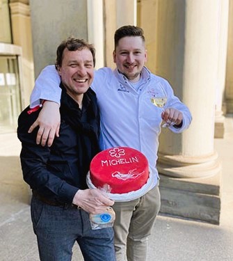 Dreamteam: Schmidt&Schmidtchen-Inhaber Falk überreicht Stefan Faeth anlässlich seines Michelin-Sternes einen roten Kuchen, auf dem mit weißem Guss Michelin steht